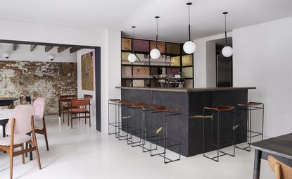 Bar area with a rustic colour palette of dusty pink, charcoal, and terracotta and original brickwork and beams, with modernist touches