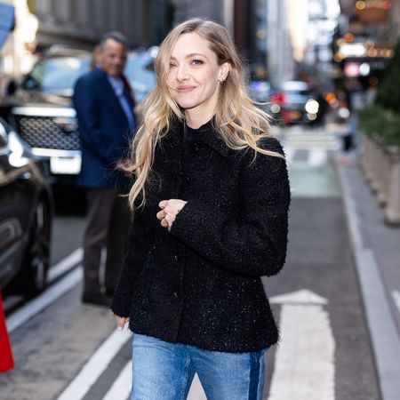 Amanda Seyfried wearing a black tweed coat, side-stripe cigarette jeans, and slingback kitten heels in NYC