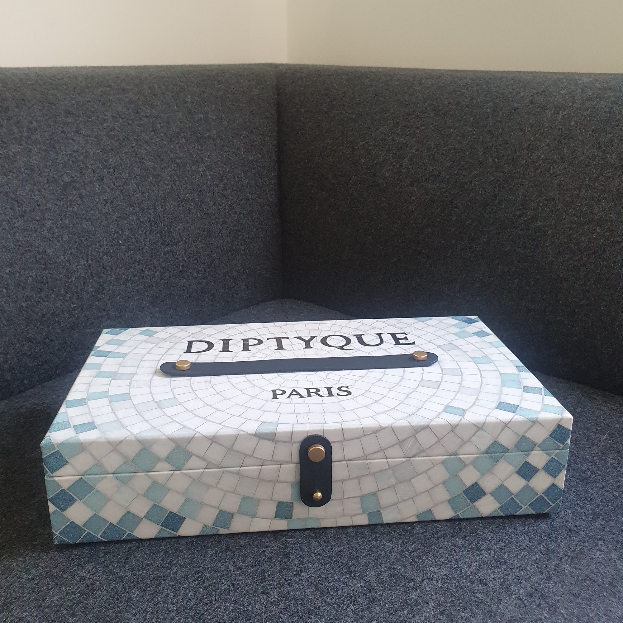 Closed Diptyque Summer Essentials calendar box on a dark grey sofa