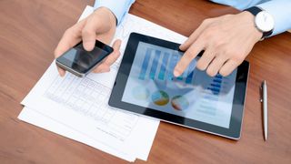 An office worker using their phone alongside their tablet