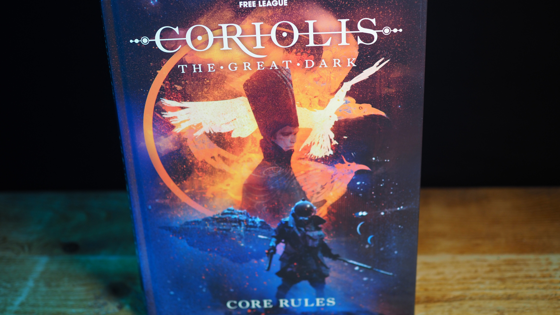 The Coriolis: The Great Dark Core Rules stood upright on a wooden surface, against a dark background
