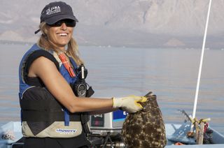 Fisler holds a halibut caught during fisheries research to reduce sea turtle bycatch in Baja California, Mexico