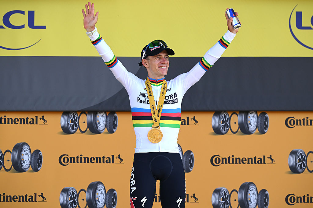 Remco Evenepoel celebrates on the podium wearing the world champion's jersey