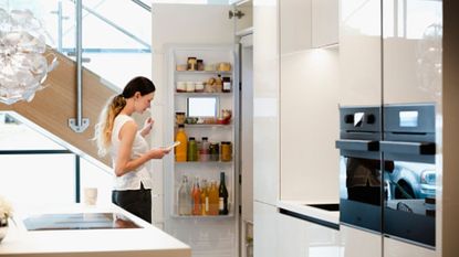 One of the best refrigerators on the market, this smart fridge is in a cream kitchen with a woman opening the door