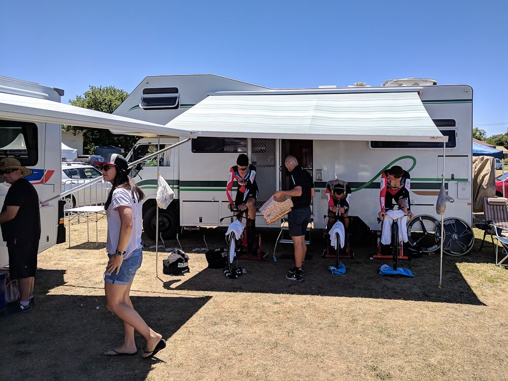 BMC Racing teammates Miles Scotson, Richie Porte and Rohan Dennis warm up in the shade of their camper van