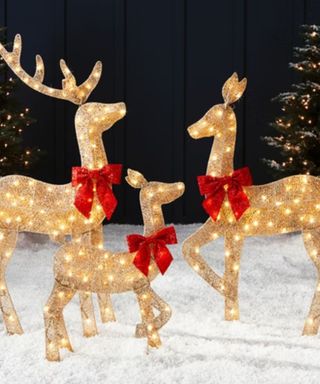 Faux Rattan Reindeer on snow against a dark background.