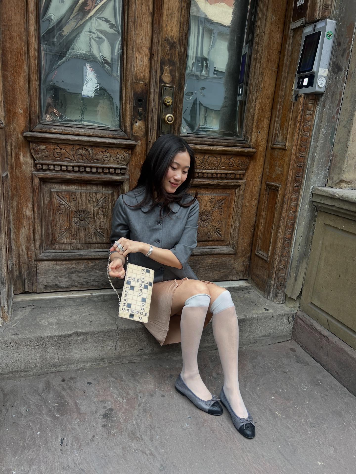An image of @vivianyrl wearing a pair of two-toned ballet flats with a champagne coloured silk skirt and a grey jacket.