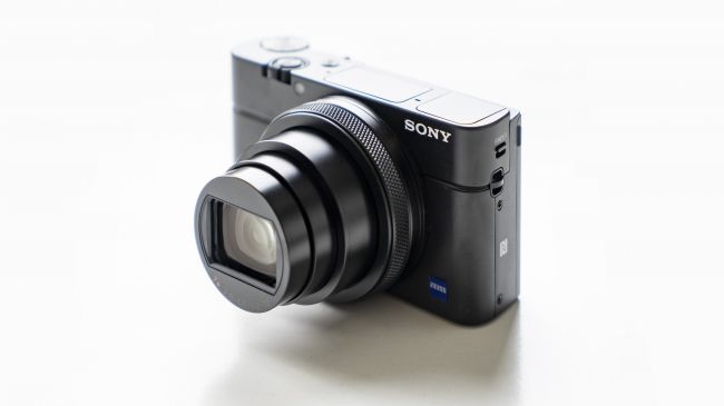 Et sort Sony Cyber-shot RX100 VI står på et hvidt bord