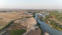 An aerial view of a river through a desert area with some vegetation