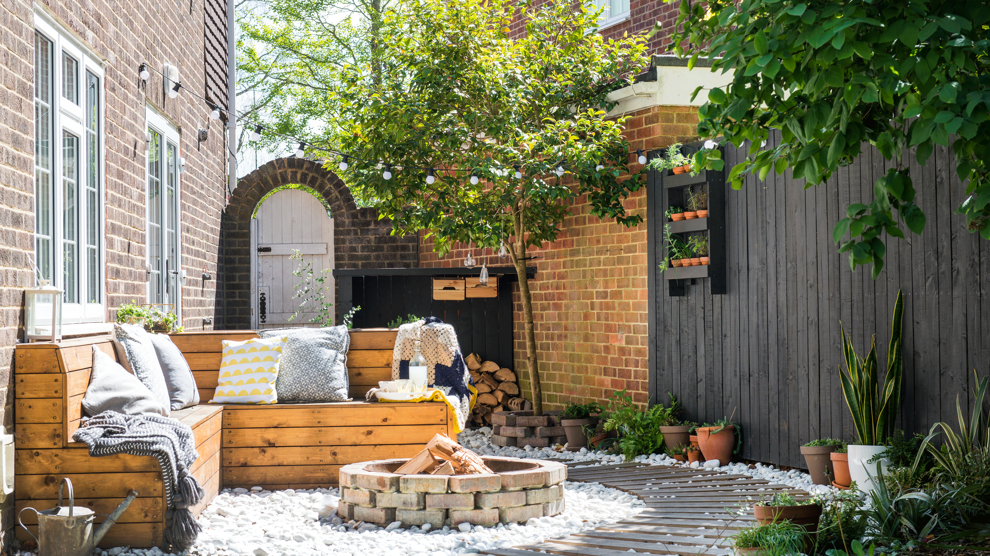 garden area with grey fence and potted plants