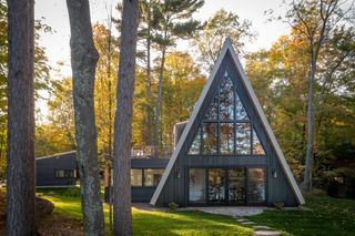 Front façade among the trees of Lake Placid A-Frame house by Strand Design