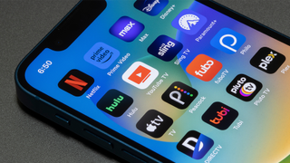 iPhone with array of streaming service icons including Disney Plus, Hulu, and Paramount Plus