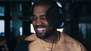 Kanye 'Ye' West wearing headphones, in front of a microphone, in jeen-yuhs: A Kanye Trilogy