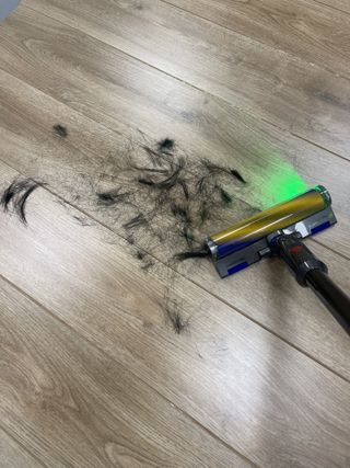 Dyson V12 Detect Slim vacuuming hair on wooden floor