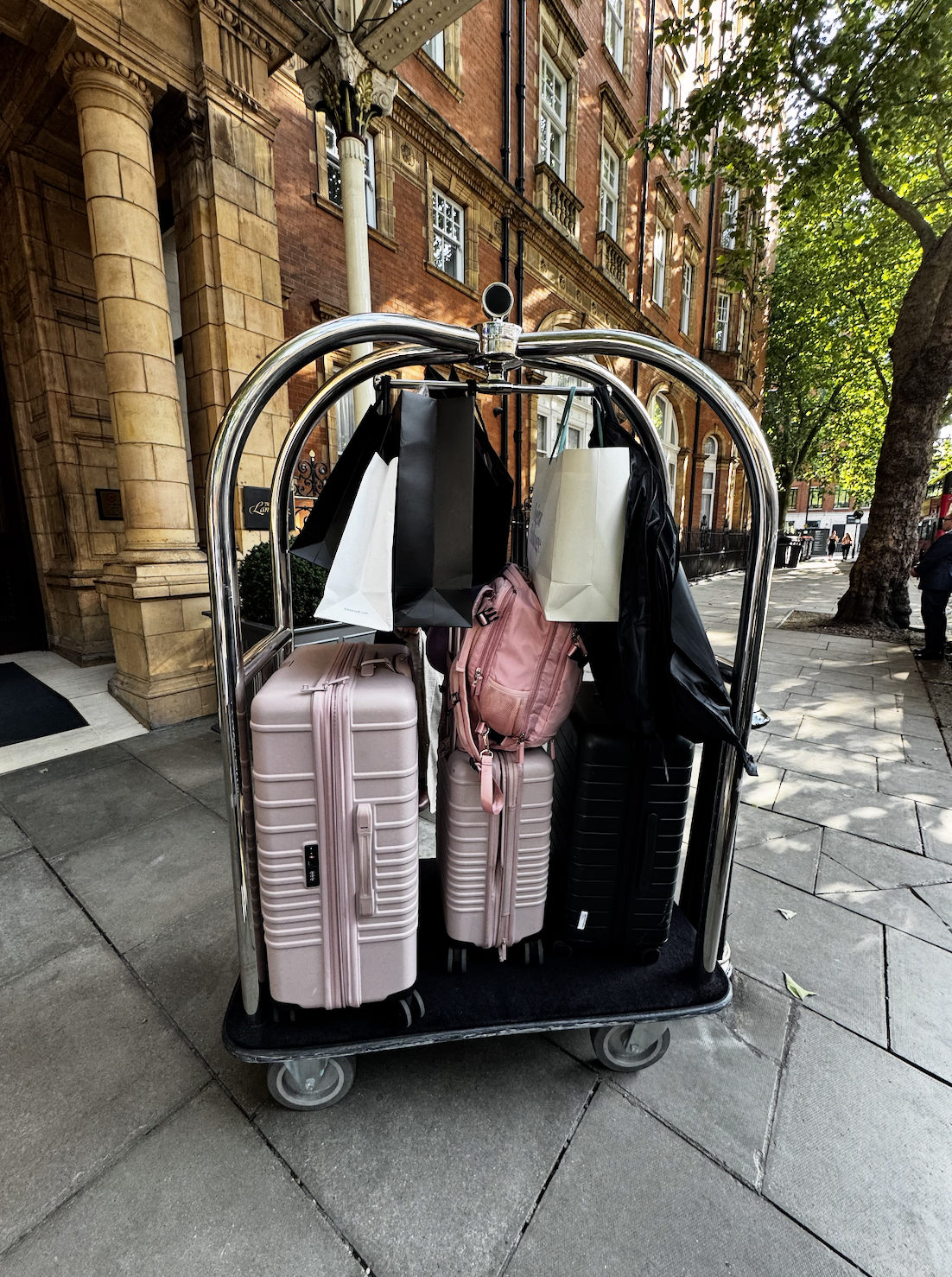 A luggage trolley filled with pink suitcases outside a hotel