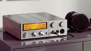 The K17 R2R Pro on a cabinet surface with a pair of over-ear headphones plugged into it.