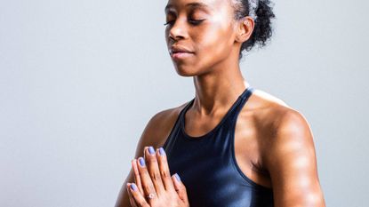 Yoga for stress, woman meditating with eyes closed and hands in prayer close to the heart