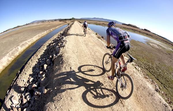 Bart Brentjens and Jelmer Piwtersma of Team Trek-Brentjens cross over a farm dam after a singletrack section on the slopes of the Matroosberg