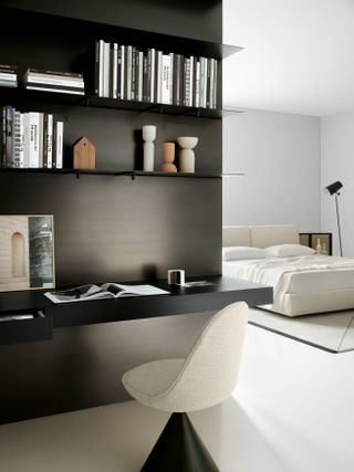 Cream cushioned seat in front of black shelving unit