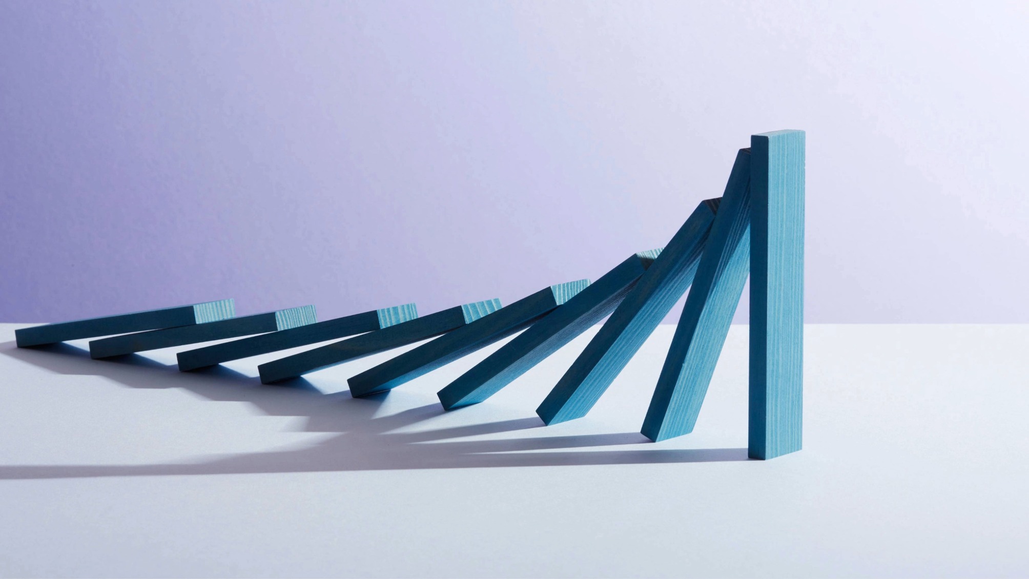 closeup of a row of falling blue wooden dominoes