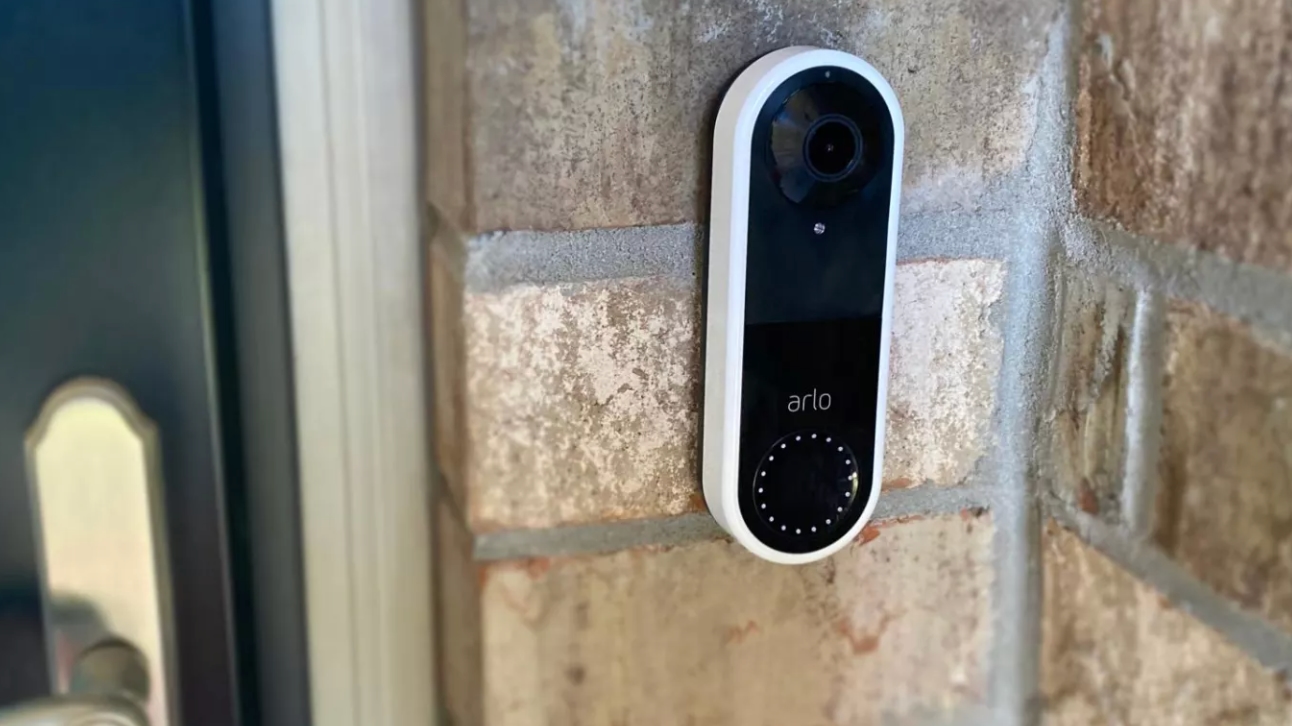 Arlo Video Doorbell on brick wall outside door.