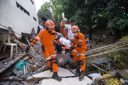 Rescue personnel evacuate an earthquake and tsunami survivor in Indonesia