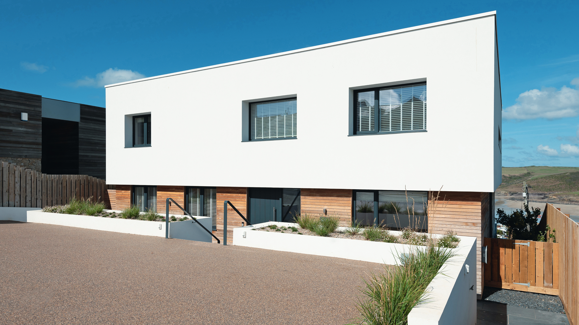 modern self build home with white render and timber clad exterior