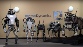 Five robots in front of Boston Dynamics sign