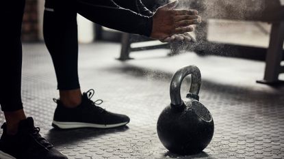 Person chalking their hands over a kettlebell in a gym