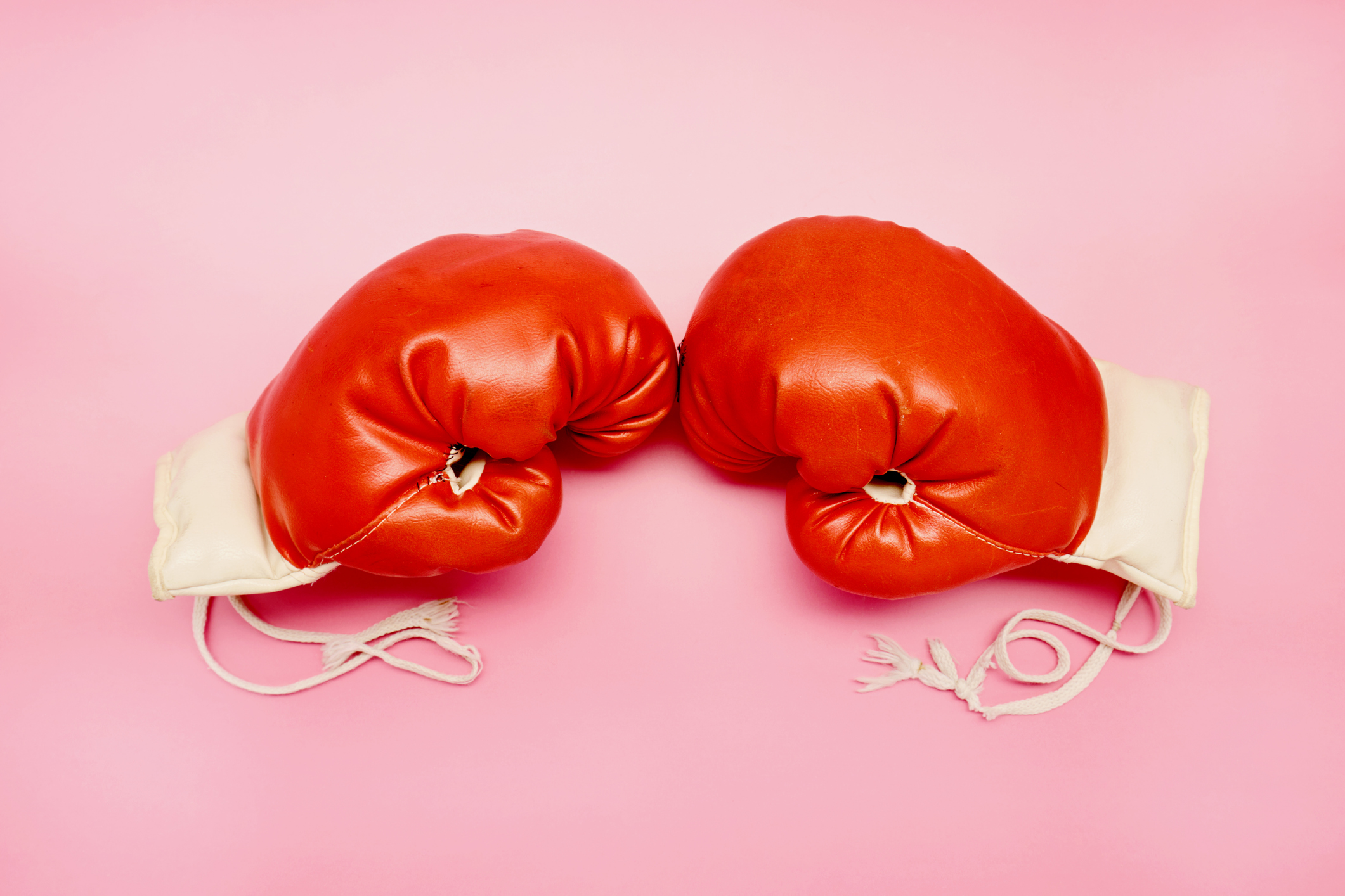 Pair of red boxing gloves on pink background