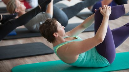 Woman performs Pilates on a yoga mat