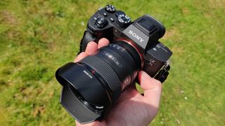 Sony 20mm f/1.8 G lens in hand