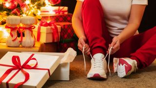 Person lacing up running shoes beside Christmas tree