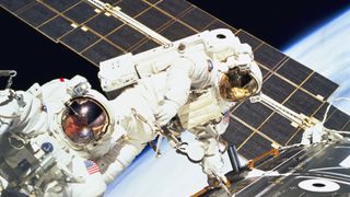 Astronauts Jerry L. Ross and James H. Newman work together on a spacewalk.