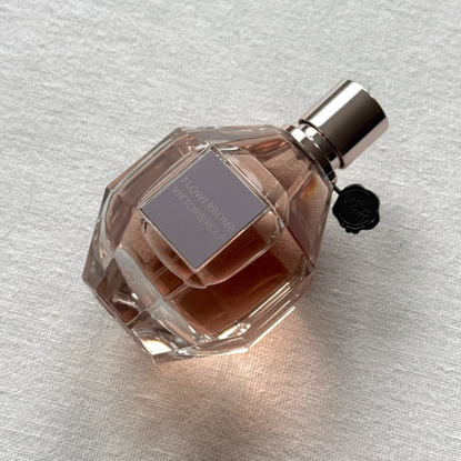 A bottle of Viktor & Rolf Flowerbomb laying at a 45 degree angle against an off-white linen background