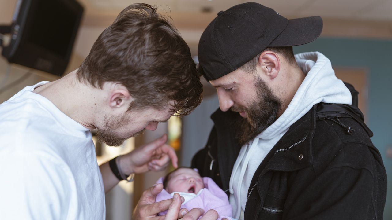 Two people holding a baby