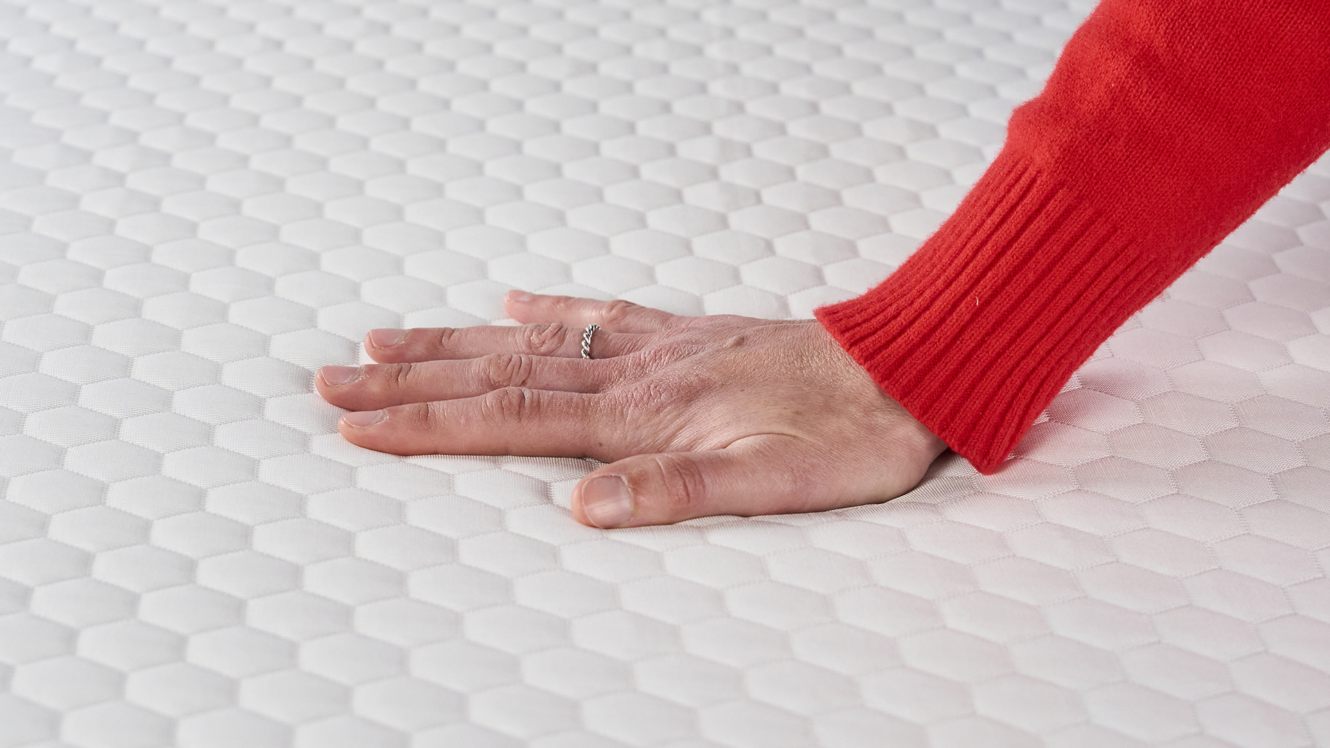 A woman's hand feels how cool the cover of the Helix Dual Comfort Mattress Topper is.