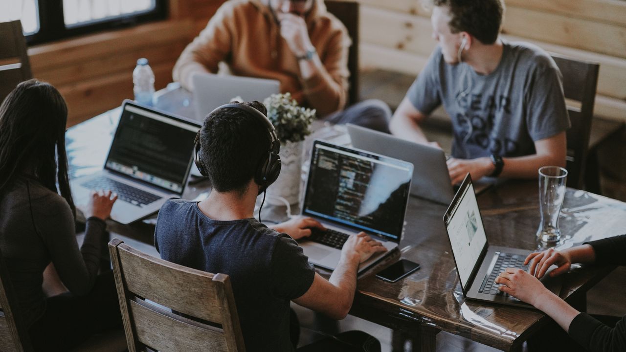 Best student laptops: students sat around desk working on their laptops 