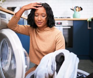 women crouching in front of appliance holding clothes with hand in head
