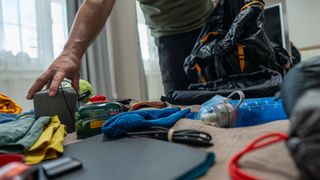 Man packing clothes into camping bag