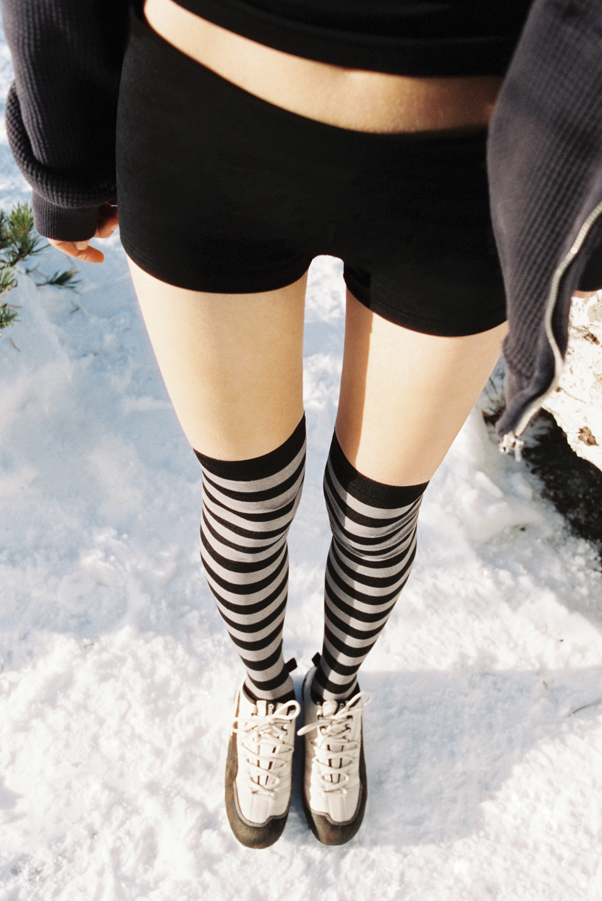 A photo from the PUMA x Danielle Guizio campaign showing a woman wearing shorts with over-the-knee striped socks and new PUMA x Danielle Guizio Klim sneakers.
