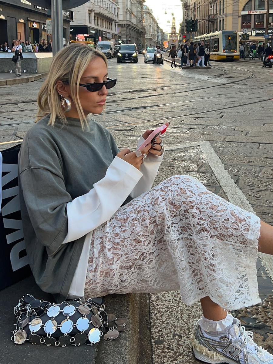 Woman wearing a lace skirt with a white long-sleeve shirt and a gray short-sleeve shirt layered over it.