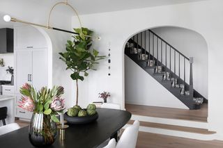 black dining table with staircase behind and white chairs
