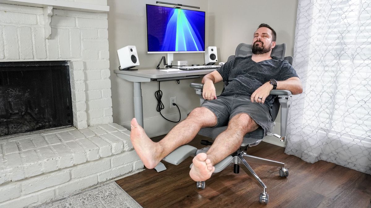 A person leaning back in the Hinomi X1 with the chair's footrest extended