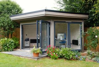 garden office with bi fold doors and small patio area