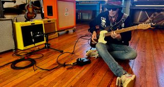 Earl Slick sits on the floor and plays his Telecaster through a Fender combo