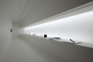 Long white lit panel with small black and white models displayed in front