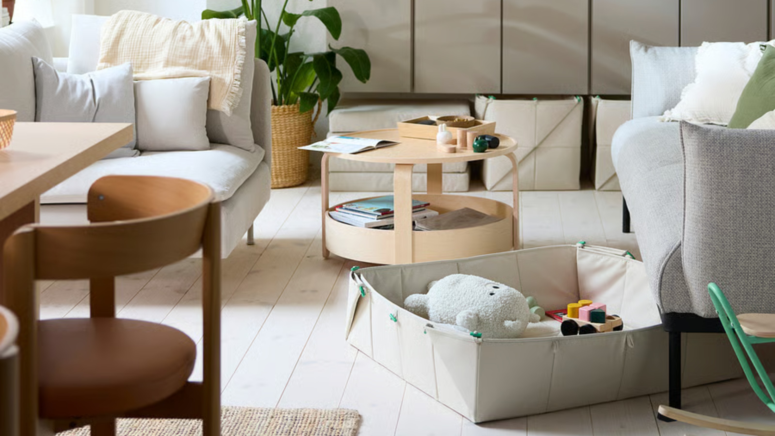 IKEA's GREJSIMOJS foldable toy storage boxes in a living room slotted under a sofa and under a sideboard
