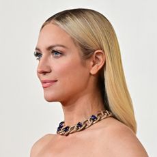 a photo of a white woman with long, blonde hair posing for paparazzi on a red carpet