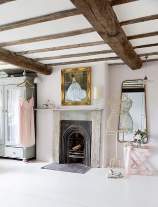 bedroom with original fireplace white painted floor ceiling beams and wardrobe